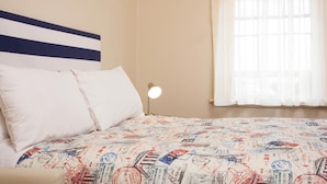 A bed with a striped headboard, a white pillow, and a patterned bedspread. - The Cally Hotel (Warrnambool)