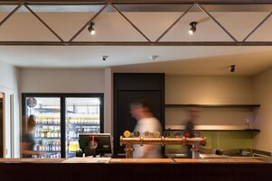 Zona de bar con grifo de cerveza, barra y una figura desenfocada al fondo.