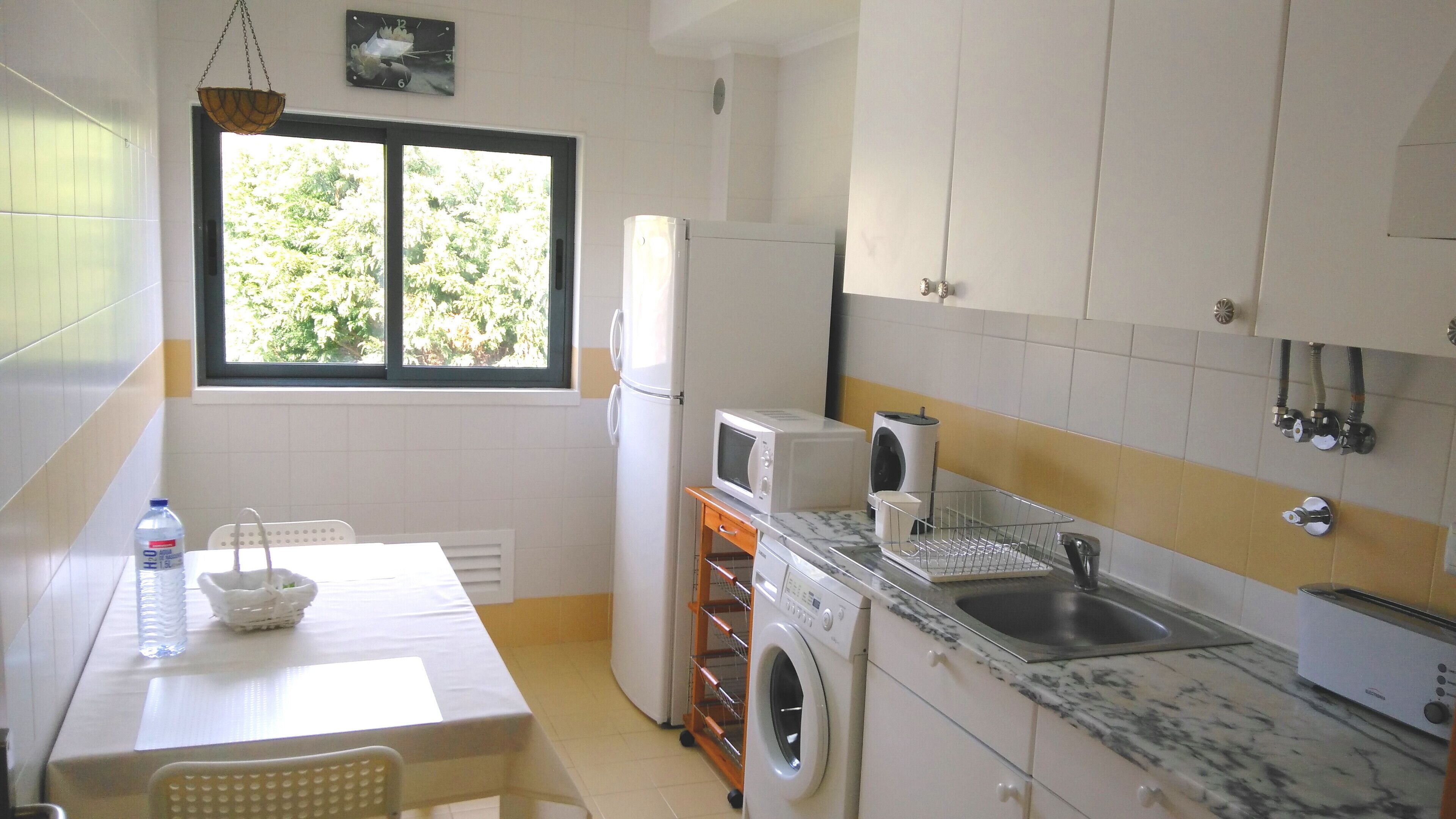 Una cucina compatta con lavatrice, forno a microonde e lavello.
