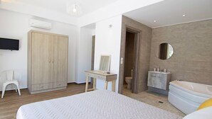 A bedroom with a large bed, a desk, a wardrobe, a TV, a bathroom with a bathtub, and a mirror. - Kalostous villa 3, Pool,Great location & Views (Agia Triada)