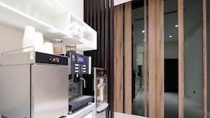 A modern coffee machine with a digital display, a milk frother, and a water dispenser. - Yu Chun Hotel (Taichung)