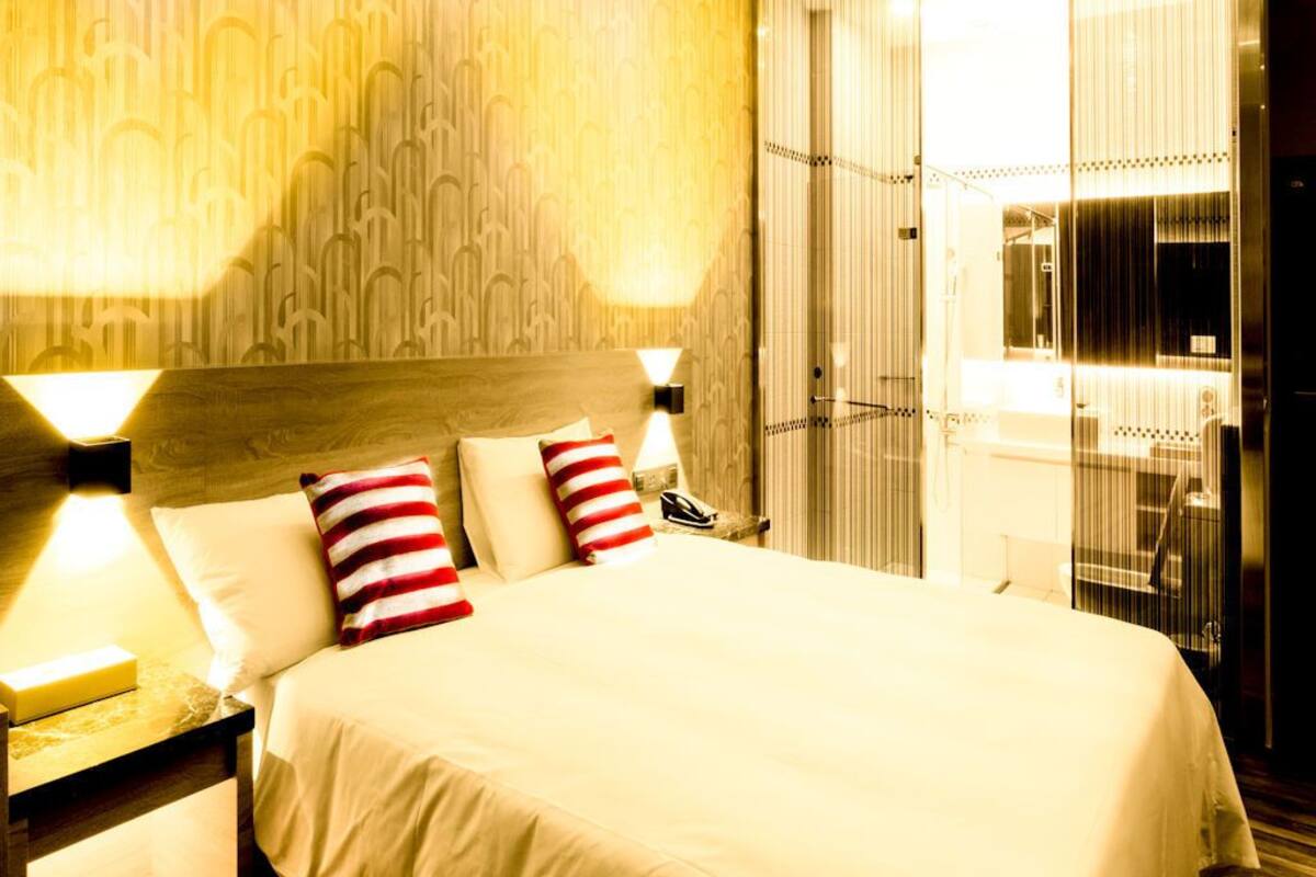 A hotel room with a large bed, two bedside lamps, and a nightstand.