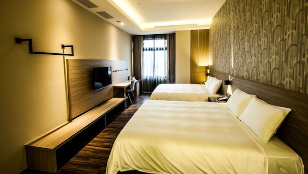 A hotel room with two beds, a desk, a TV, and a patterned wall. - Yu Chun Hotel (Taichung)