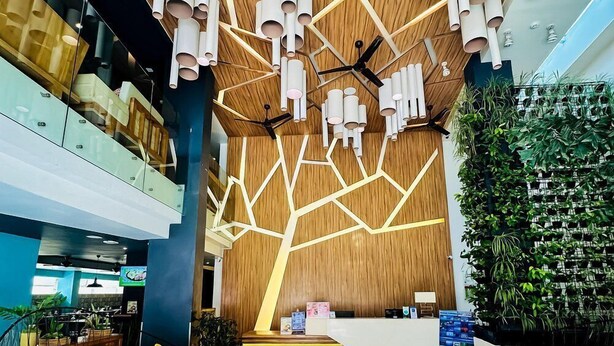 Un hall d’entrée moderne avec un plafond en bois, des sièges jaunes et une table basse en verre.