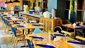 Un restaurant doté de nombreuses tables, de chaises et de plantes suspendues.