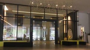 A modern hotel lobby with glass doors, a reception desk, and a unique metal sculpture. - Bochang Homestay (Kuala Lumpur)