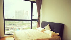 A bedroom with a large window, a bed with a dark headboard, and a view of a cityscape and highways. - Bochang Homestay (Kuala Lumpur)