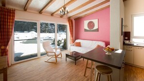 A cozy room with a wooden ceiling, a white sofa, a dining table with fruit, and a view of a snowy landscape. - Arrive - holidays - refueling in "House on Forest Park" (Scheidegg-Lindenau)