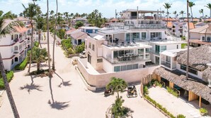 Een modern resort met meerdere gebouwen, een centrale binnenplaats en palmbomen.