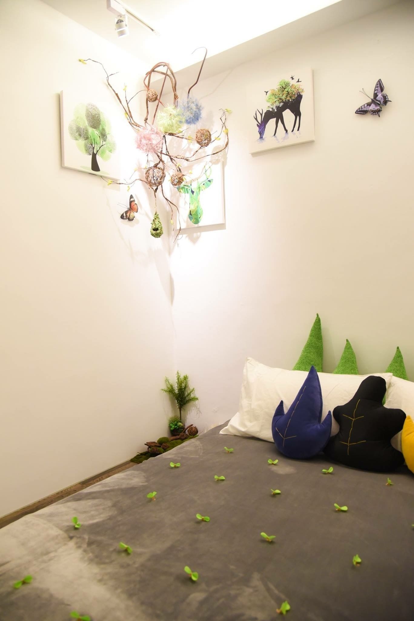 Un dormitorio con una cama, almohadas, una obra de arte en la pared y una planta pequeña.
