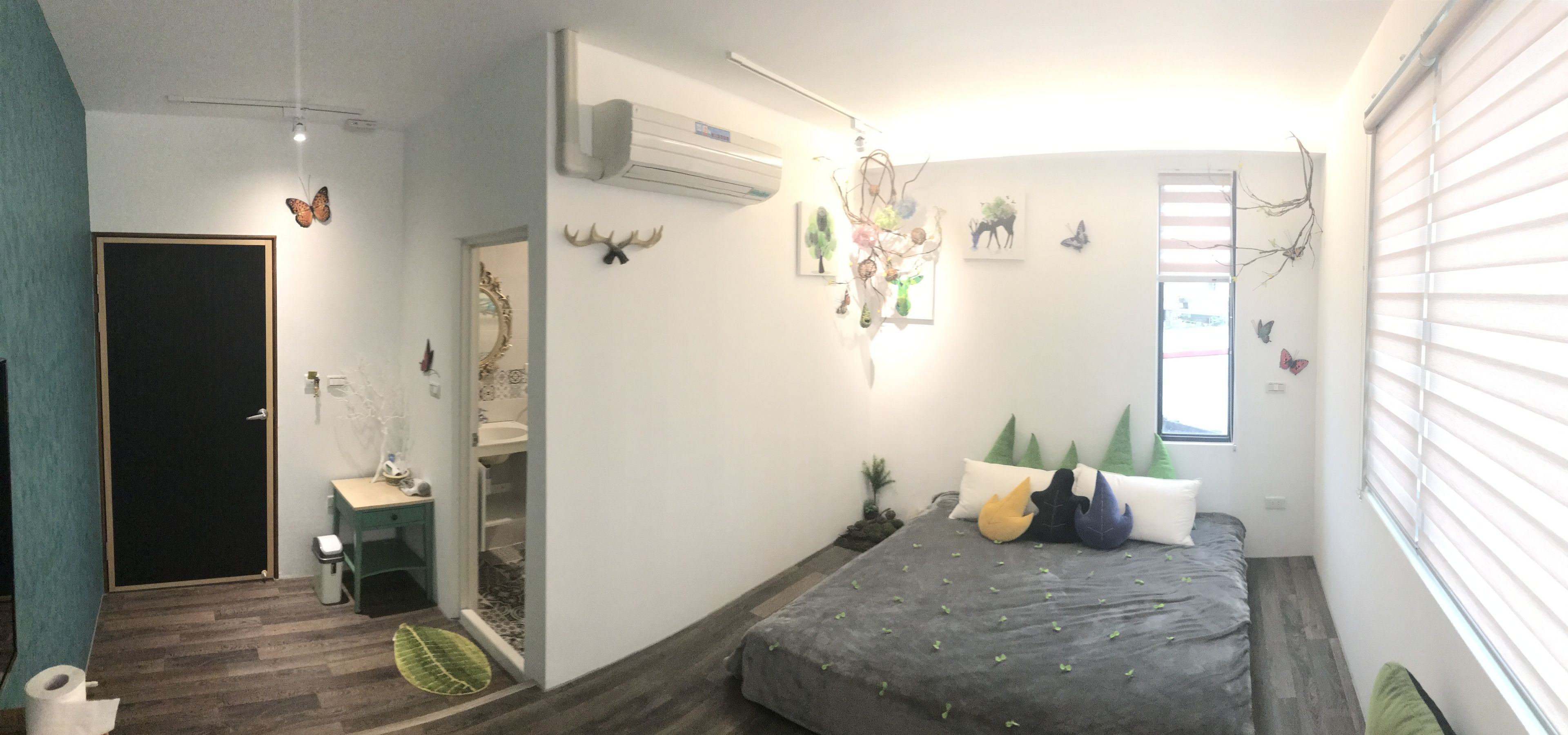 A bedroom with a bed, a window, a mirror, and a door.