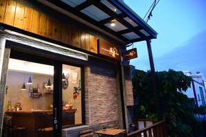 A restaurant with a wooden exterior, a stone wall, and a signboard.