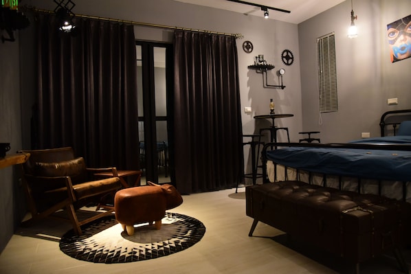 A modern bedroom with a bed, a leather sofa, a small round table, and a chair.