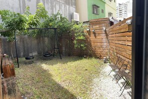 A backyard with a swing set, a wooden bench, and a wooden fence. - Living house (Hengchun)