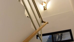A staircase with wooden handrails and a wall-mounted light fixture. - Living house (Hengchun)