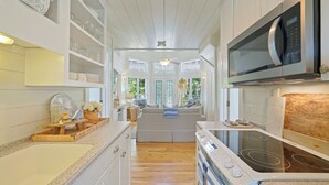 A modern kitchen with white cabinetry, a built-in microwave, a stove, and a large window providing natural light.