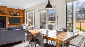 Een moderne keuken met een houten tafel, stoelen en een groot raam met uitzicht op de omgeving.