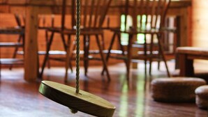 A wooden dining table with chairs and a hanging wooden object. - Private Lodge COTENCHI (Nakijin)