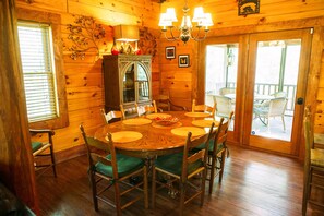Una sala da pranzo in legno con un tavolo rotondo, sedie e un lampadario.