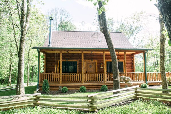 Una baita di legno con un portico, immersa tra gli alberi.