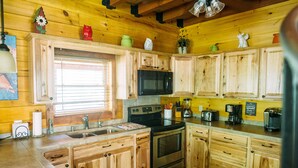 A kitchen with wooden cabinets, a sink, a stove, and a microwave.