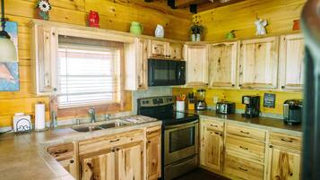 A kitchen with wooden cabinets, a sink, a stove, and a microwave.