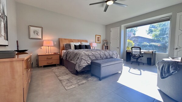 A bedroom with a bed, bedside tables, a desk, and a chair.