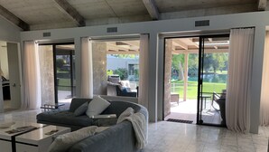 A spacious living room with a grey sofa, a coffee table, and a view of a patio area with outdoor furniture.