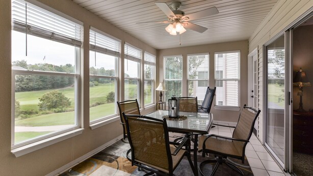 A dining area with a glass table, chairs, and a ceiling fan.