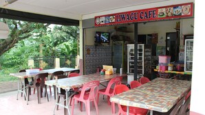 A cafe with outdoor seating, a tiled floor, and a signboard. - Liwagu Lodge (Ranau)