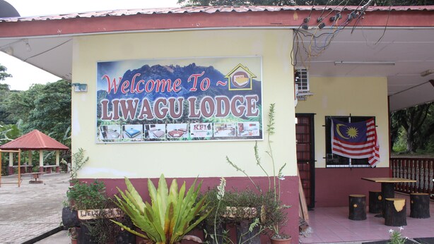 A sign welcoming visitors to Liwagu Lodge, featuring a mountain backdrop and various amenities. - Liwagu Lodge (Ranau)