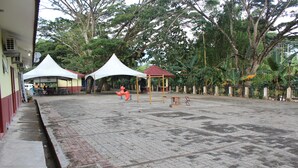 An outdoor area with paved ground, a gazebo, and a tented structure. - Liwagu Lodge (Ranau)