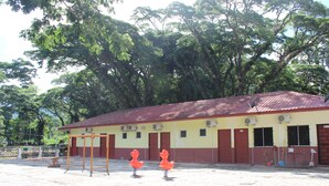 A building with a red roof and yellow walls, surrounded by trees. - Liwagu Lodge (Ranau)