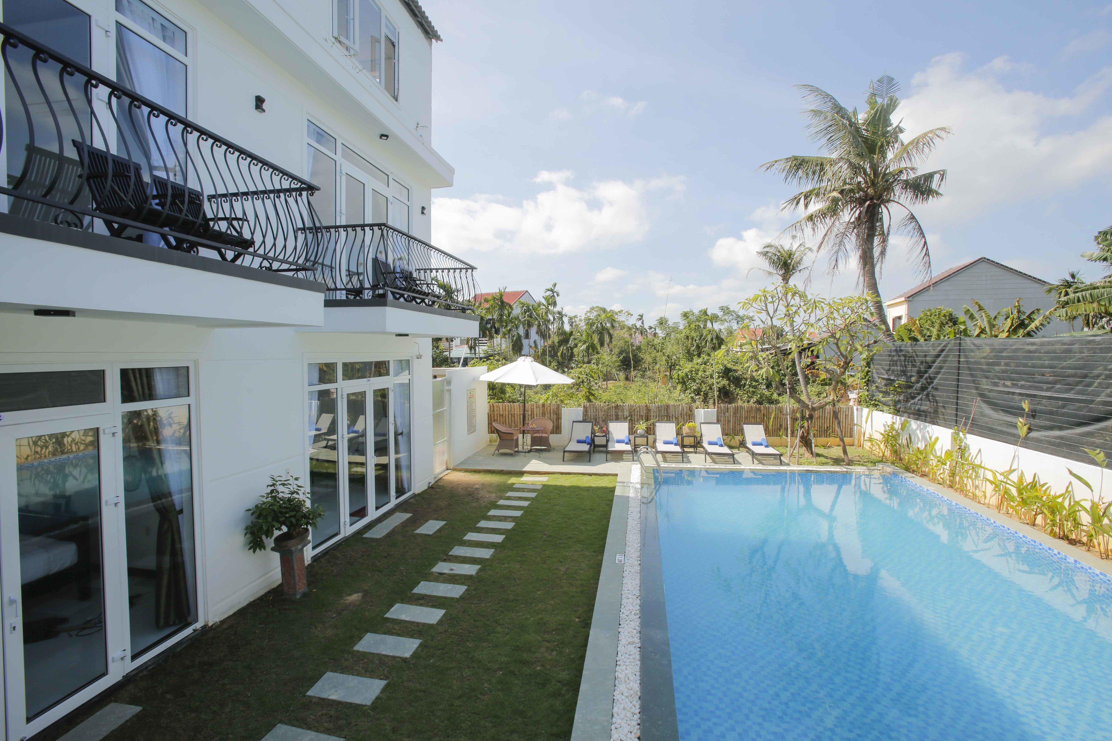 Ein modernes, zweistöckiges Haus mit Swimmingpool, einem Balkon mit Gartenmöbeln und einem gepflegten Rasen.
