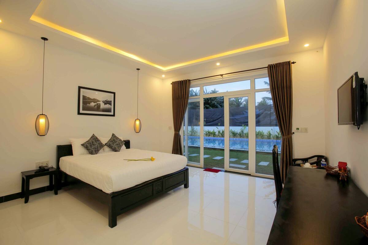 Une chambre moderne avec un grand lit, un téléviseur à écran plat et une porte-fenêtre coulissante donnant sur un balcon.