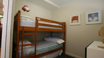 A bunk bed room with a wooden frame, a small desk, and two framed pictures on the wall.