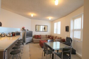 Una cocina moderna con barra, una mesa de comedor con sillas, un sofá y un televisor.