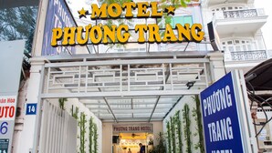 Der Eingang zum Phoong Trang Hotel mit deutlich sichtbarer Beschilderung, einem überdachten Eingangsbereich und Pflanzen in Töpfen entlang des Weges.