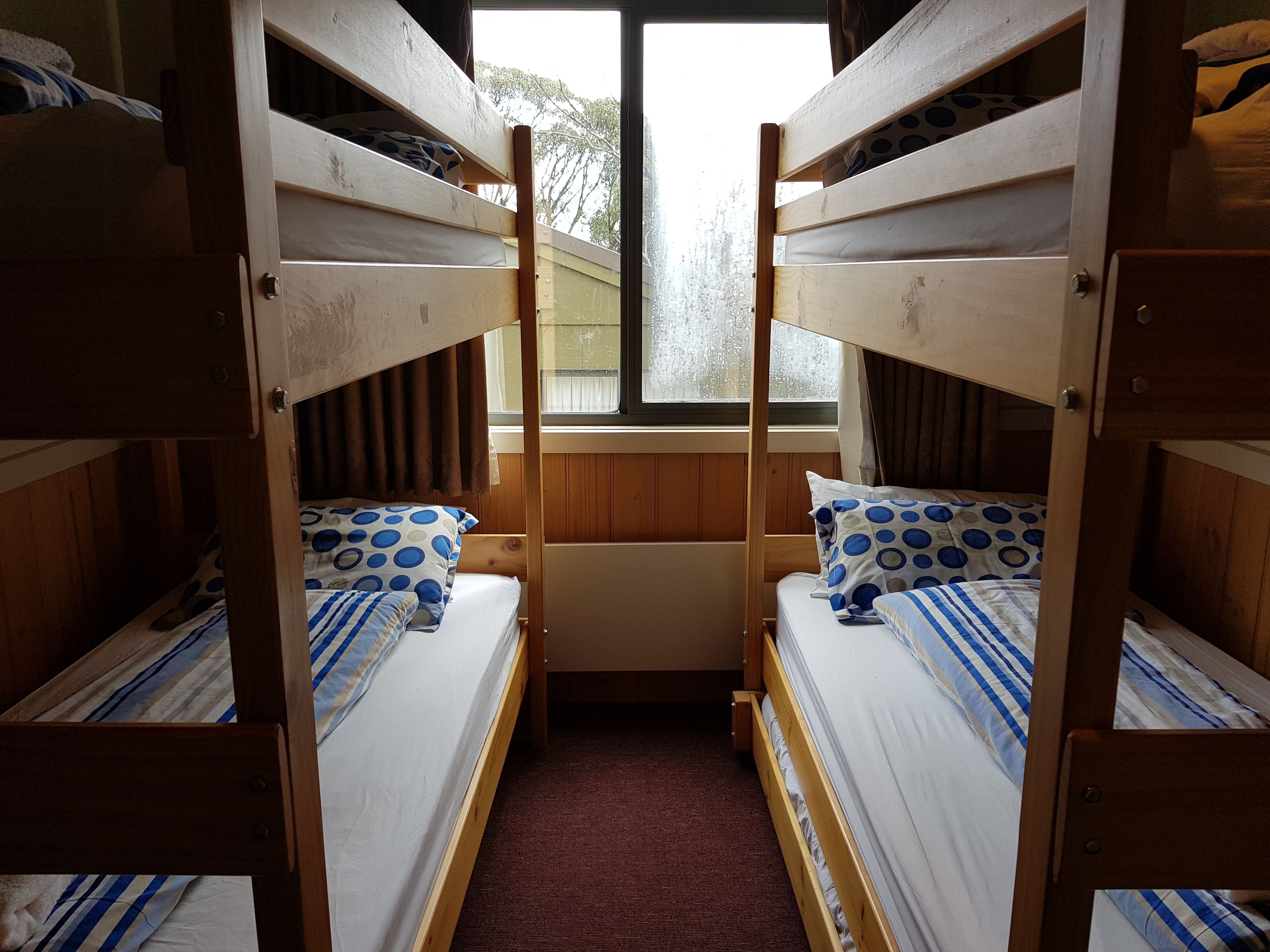 A room with two bunk beds, each with a pillow and a striped blanket.