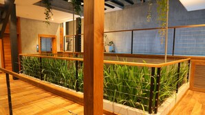 Un balcón de madera con vistas a un paisaje urbano, con barandilla y plantas en macetas.