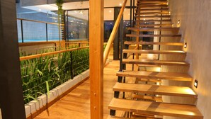 Una escalera moderna con escalones de madera y barandillas de metal, que sube a un nivel superior.