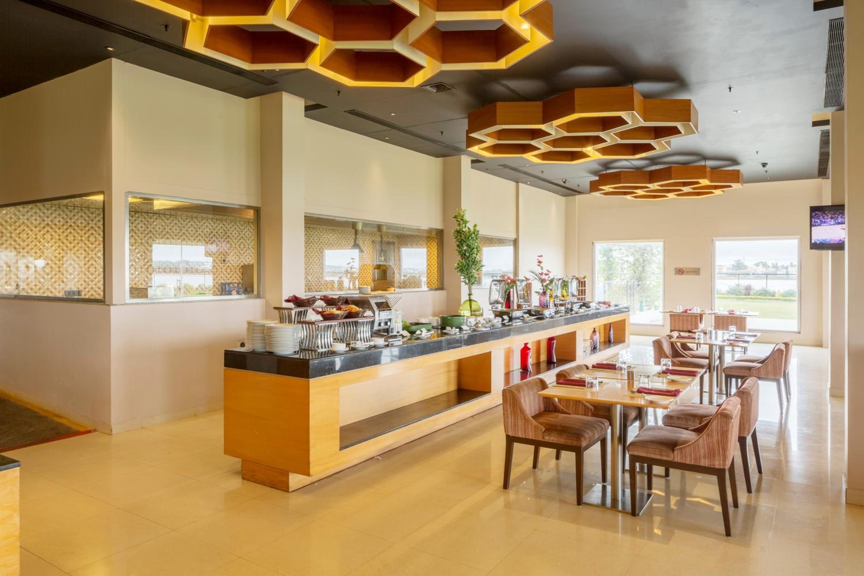 Un hall d’hôtel moderne doté d’un long comptoir, d’un espace salon et d’un plafond à la forme hexagonale unique.