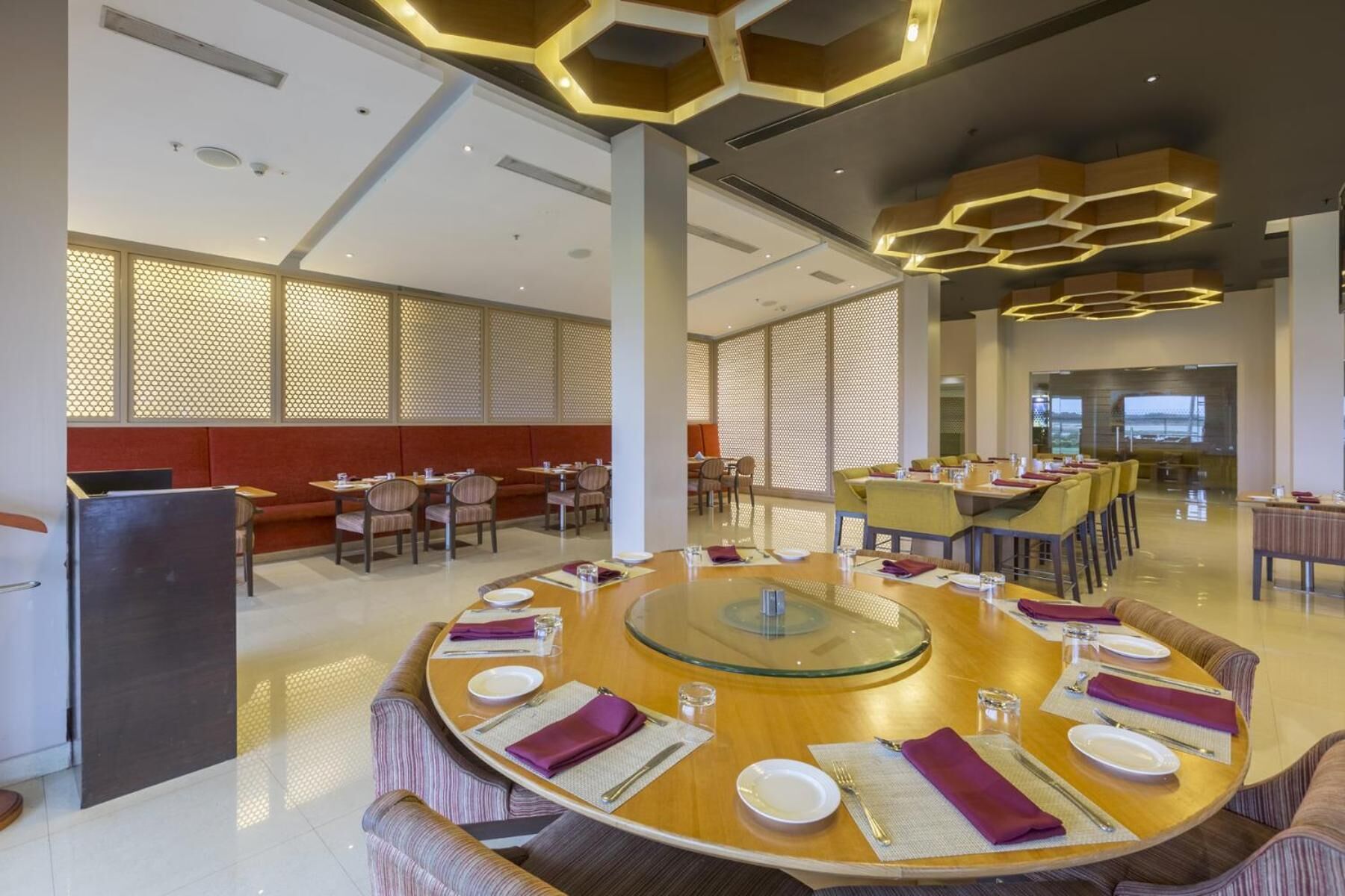 A modern dining area with round tables, cushioned seating, and a view of the outdoors.