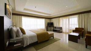 Una habitación de hotel con cama, televisión, sofá y escritorio.