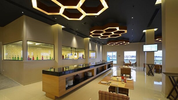 Un moderno hall de hotel con un amplio mostrador de recepción, zona de estar y grandes ventanales con vistas.