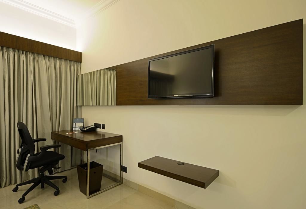 A modern office space with a desk, chair, and a mounted TV.