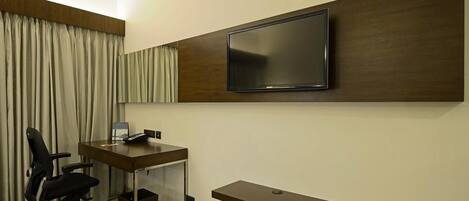A modern office space with a desk, chair, and a mounted TV.