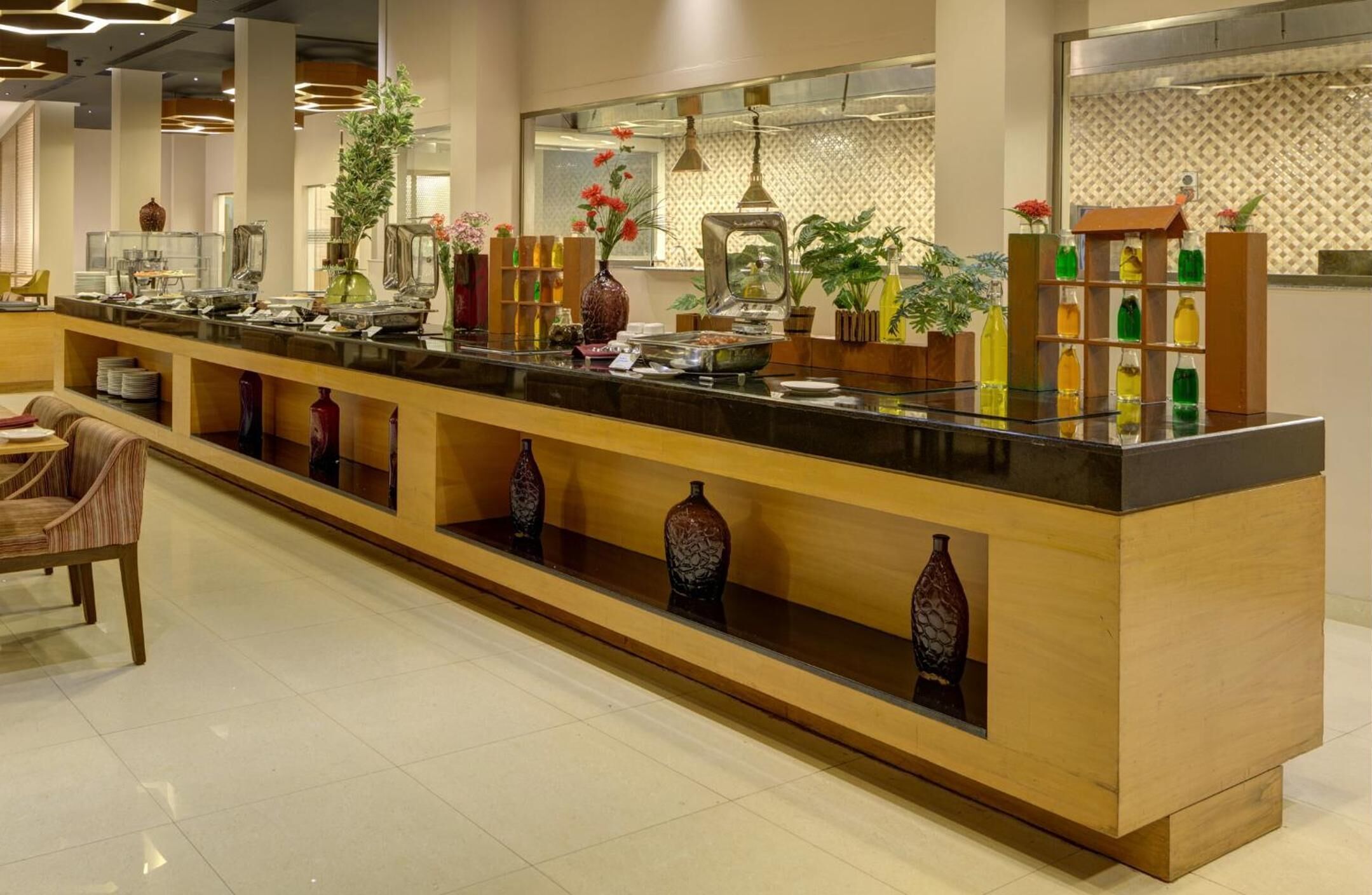 A buffet area with a long counter, various food items, and decorative vases.