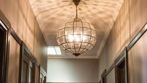 A hallway with patterned flooring, a geometric ceiling light, and dark wooden doors. - Nags Head Hotel (Adamstown)
