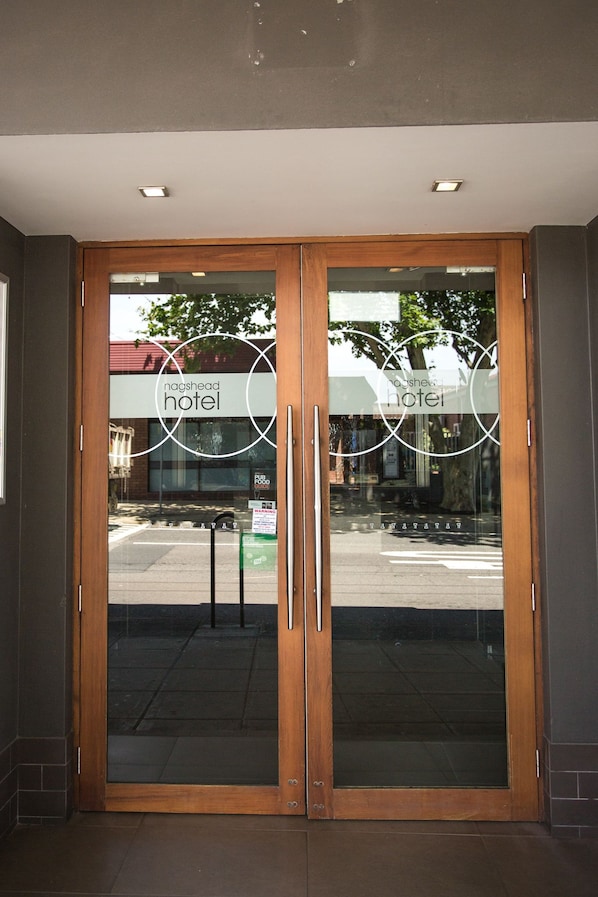 A hotel entrance with double glass doors and a wooden frame.
